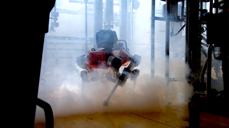Autonomous four-legged inspection robot navigating through smoke in an industrial plant during safety inspection.